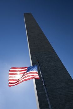 USA flag in the wind dark sky, the sun and Washington Monument