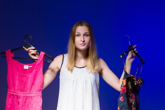 Beautiful young woman show is clothe on a blue background. Horizontal frame