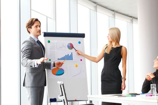 Workers at business meeting looking at presentation of financial reports in modern office