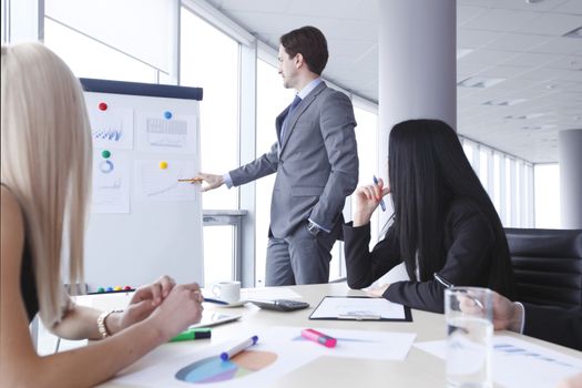 Workers at business meeting looking at presentation of financial reports in modern office