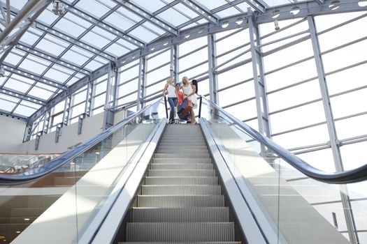 Young beautiful happy women on escalator of shopping mall