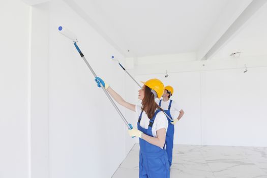 two workmen painting white wall