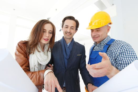 foreman shows house design plans to a young couple