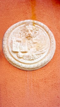 lion in circular shape bas relief art on orangel wall in Venice, italy