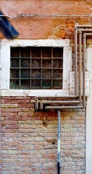 rustic metal pipe and window on decay brick wall in Venice, Italy      