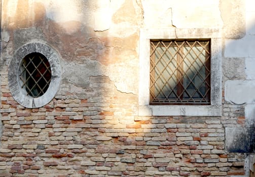 two windows in square and oval shape with brick wall building in Venice, Italy