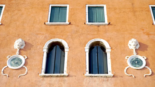 Windows on orange brown wall building architecture, Venice, Italy