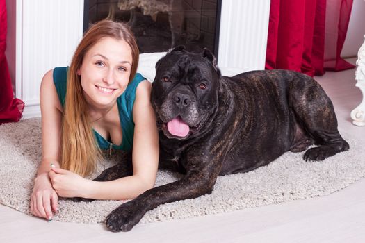 woman is at home next to the fireplace with his  dog Cane Corso