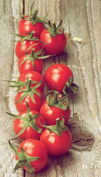 Ripe Cherry Tomatoes with Stems In a Row on Rustic Wooden background. Focus on Foreground. Retro Styled