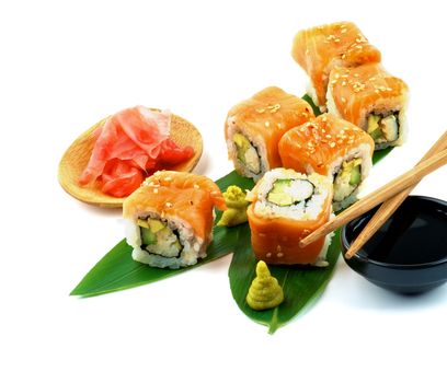 Delicious Maki Sushi with Salmon, Crab, Avocado and Cheese on Green Palm Leafs with Soy Sauce, Ginger and Pair of Chopsticks closeup on white background