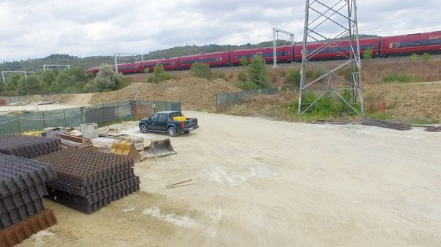 Fast moving train speeding up near a building site. Industrial environment.