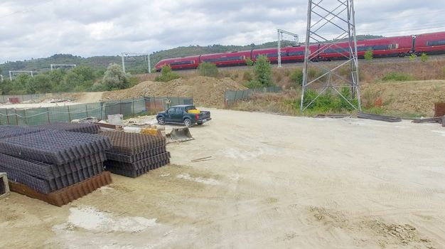 Fast moving train speeding up near a building site. Industrial environment.