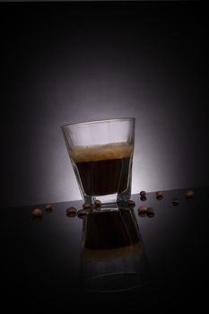 Espresso in glass with coffee beans and crane sugar cubes on dark background. Gourmet luxurious coffee drinking.