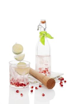 Delicious pomegranate lemonade with lime isolated on white background. Culinary fresh mocktail, non alcoholic summer drink. 