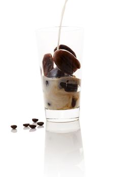 Milk coffee. Pouring milk on frozen coffee in coffee bean form in glass on white background. Culinary coffee drinking. 