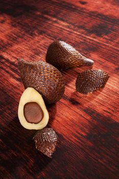 Delicious salak fruit on brown wooden textured background. Tropical fruit, rustic styles.