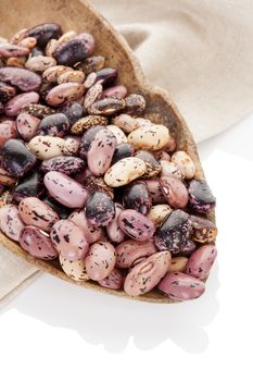 Pinto beans on wooden scoop on beige table cloth. Healthy eating, agriculture background.