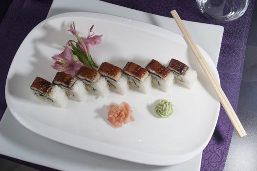 set of sushi rolls served with wasabi and ginger on white plate