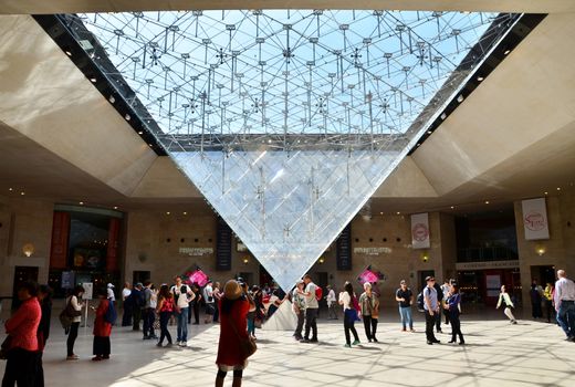 Paris, France - May 13, 2015: Tourists visit Inside the Louvres pyramid on May 13, 2015 in Paris. Louvre is one of the biggest Museum in the world, receiving more than 8 million visitors each year. 