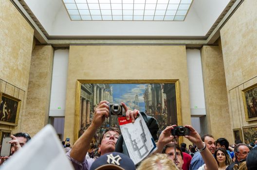 Paris, France - May 13, 2015: Visitors take photos of Leonardo DaVinci's "Mona Lisa" at the Louvre Museum on May 13, 2015 in Paris, France. The painting is one of the world's most famous.
