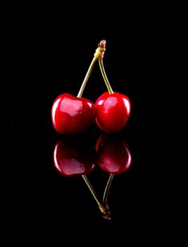 Ripe juicy cherries standing on black background.