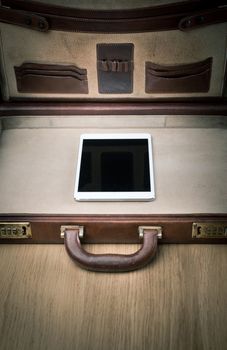 Open leather brefcase on parquet with only digital tablet inside.