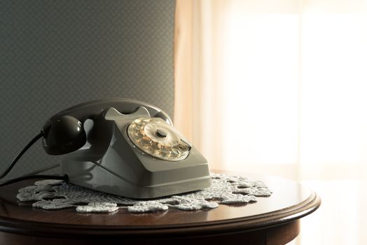 Vintage telephone on doily and wooden table in the living room.