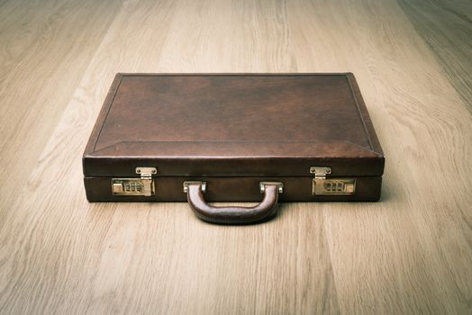 Leather vintage briefcase on hardwood floor with safety lock.
