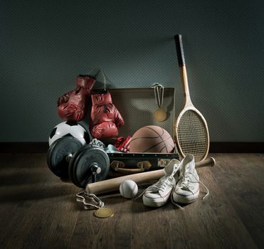 Teenager sport equipment in a vintage suitcase including sports footwear, boxing gloves, weights and baseball bat.