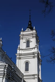 Side view of the tower of Roman Catholic Cathedral in Ludza, Latvia, on navy blue sky background.