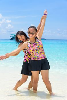 Female tourists mother and daughter in swimsuits smiling happily on the beach at Koh Miang island is a beautiful attractions famous of sea in Mu Ko Similan National Park, Phang Nga Province, Thailand