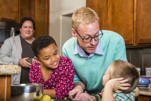 Gay men preparing a meal with children in residential kitchen