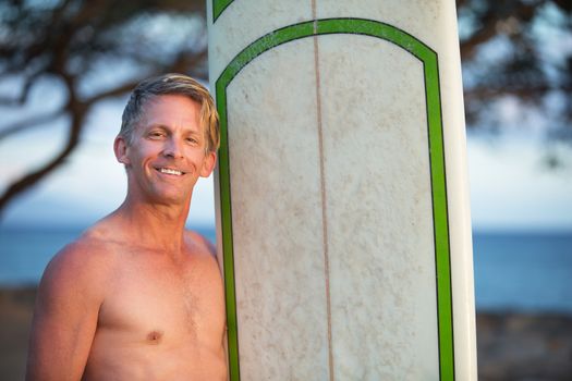 Handsome single adult male with surfboard outdoors