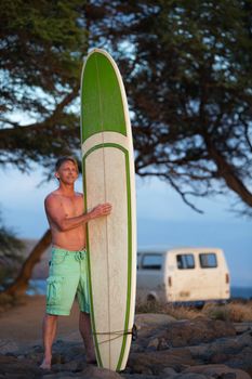 Determined single man holding surfboard near van on beach