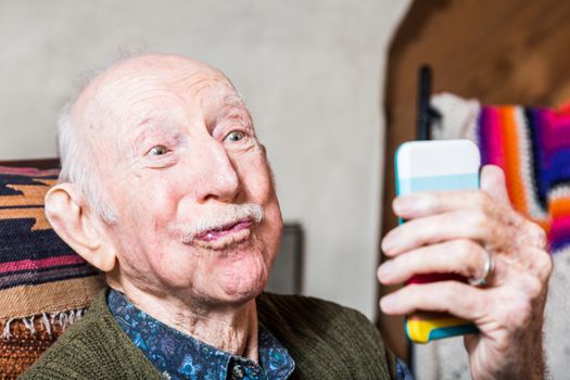 Older man looking at camera while taking silly face selfie