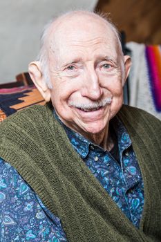 Older gentleman in green vest smiling into the camera