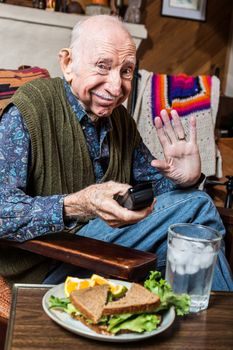 Elderly man alone in green vest with sandwich