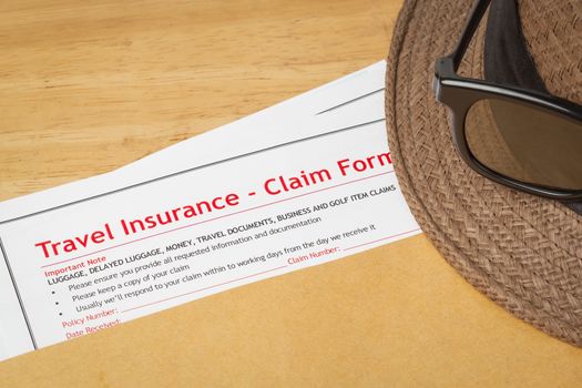 Travel Insurance Claim application form and hat with eyeglass on brown envelope, business insurance and risk concept; document is mock-up