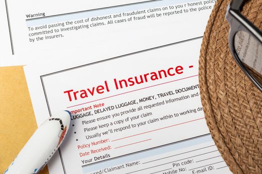 Travel Insurance Claim application form and hat with eyeglass on brown envelope, business insurance and risk concept; document and plane is mock-up