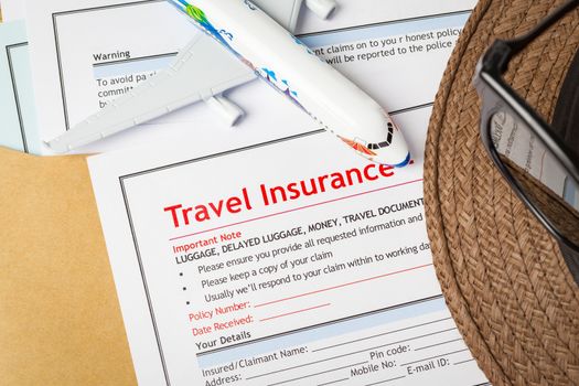 Travel Insurance Claim application form and hat with eyeglass on brown envelope, business insurance and risk concept; document and plane is mock-up