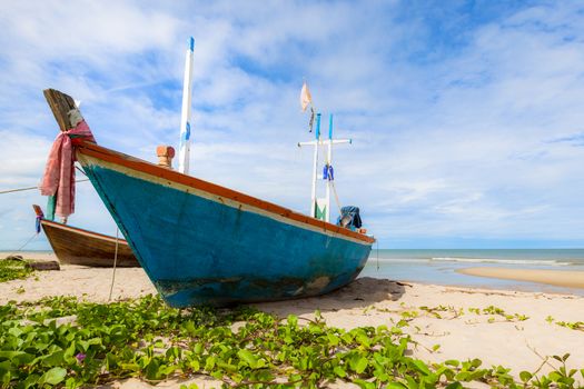 Fishing boat on sand beach and blue sky
