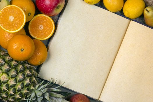 An open menu book with blank pages and a selection of fresh fruit.