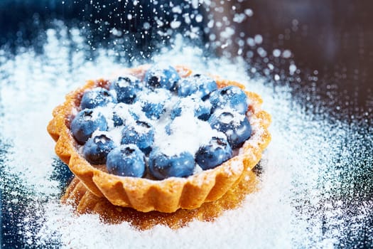 Tartlet with fresh blueberries. Background with copy space.