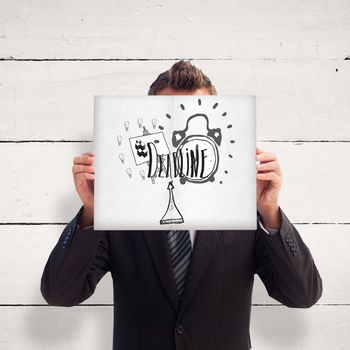 Businessman holding a white card in front of his face against white wood