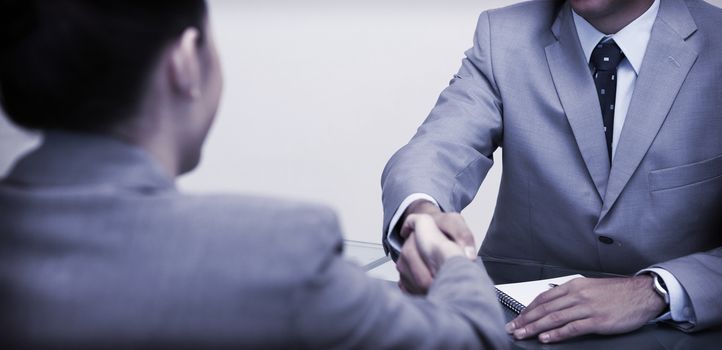 Young business partners sitting at a table shaking hands