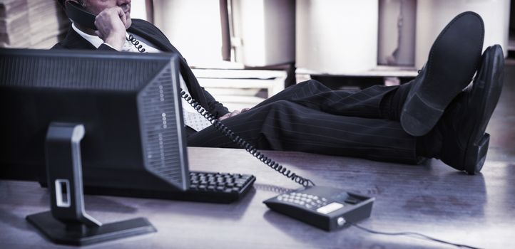 Relaxed warehouse manager using telephone at desk