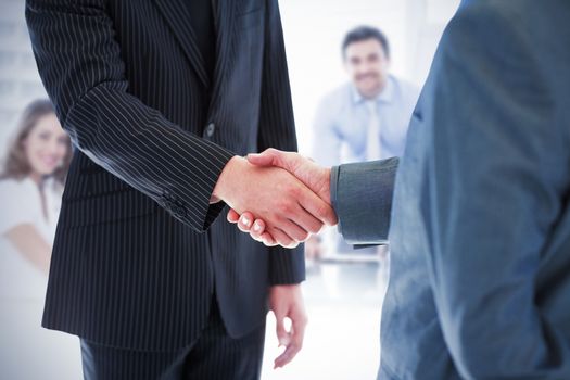 Business people shaking hands against business people in office at presentation