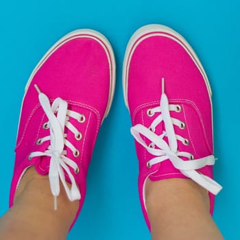 Legs in pink sneakers on a blue background