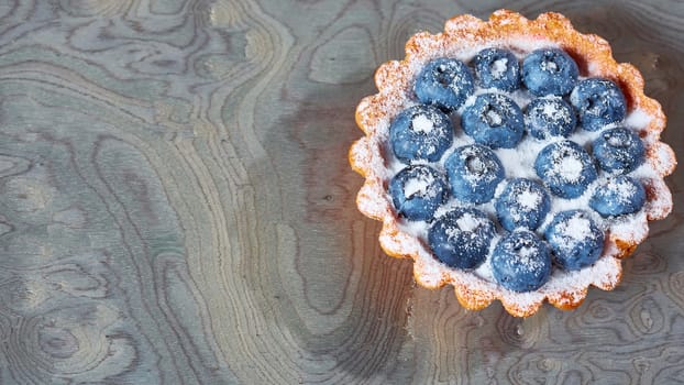 Tartlet with fresh blueberries. Background with copy space.