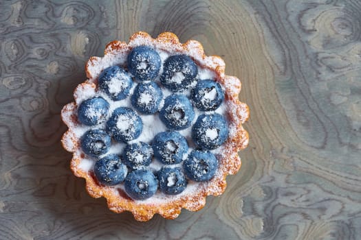 Tartlet with fresh blueberries. Background with copy space.